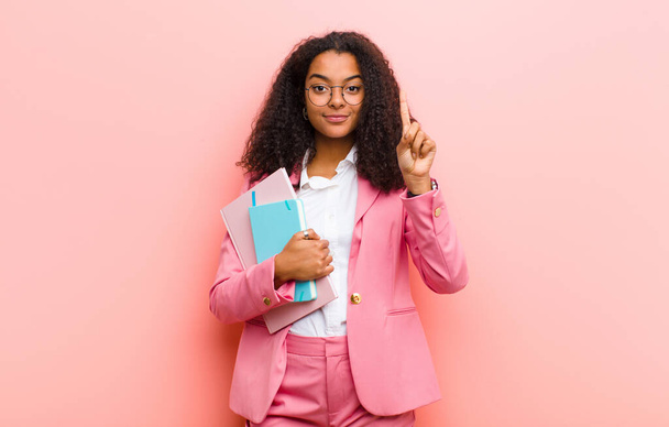 young black pretty business woman with books against pink wall background - Foto, Imagem