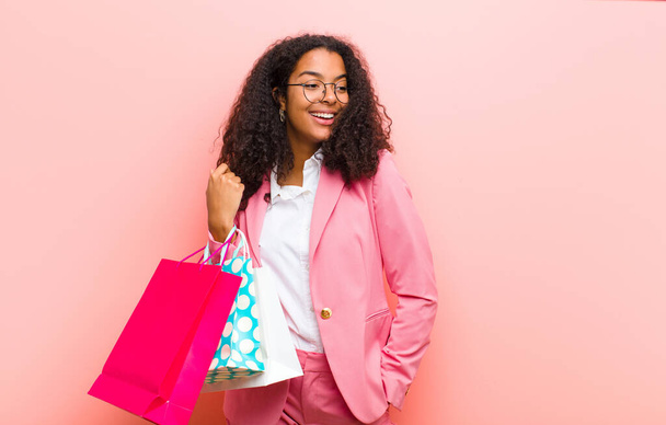 young black pretty woman with shopping bags against pink wall background - Photo, image