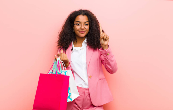 young black pretty woman with shopping bags against pink wall background - Valokuva, kuva