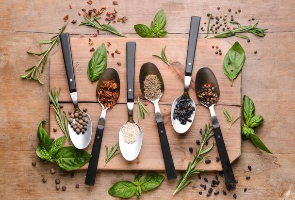 Spoons with different spices on wooden background - Photo, image