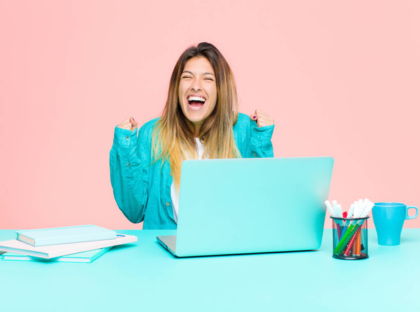 young pretty woman working with a laptop looking extremely happy and surprised, celebrating success, shouting and jumping - Foto, Imagen
