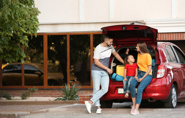 Happy family near car with open trunk on street - Photo, Image