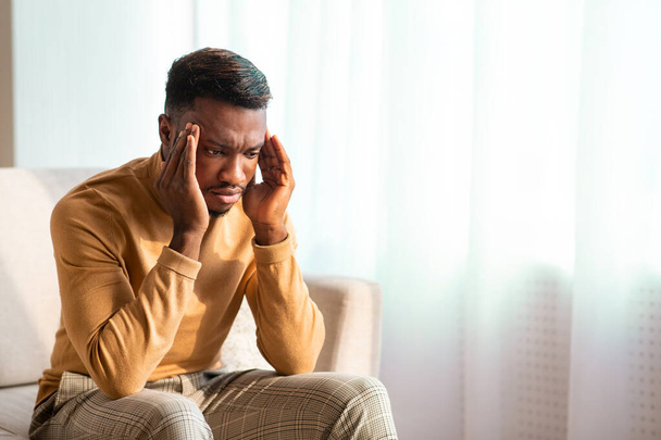 African American Man Suffering From Headache Sitting At Home - 写真・画像