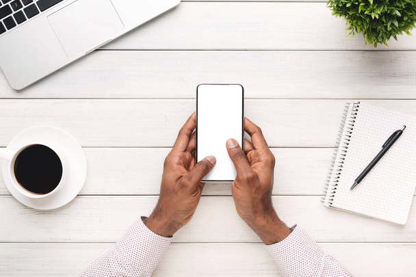Black man using modern smartphone with blank screen at workplace - Fotografie, Obrázek