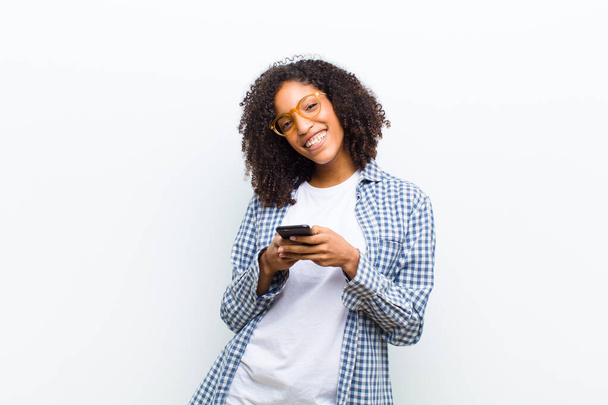 young pretty black woman with a smart phone against white wall - Foto, afbeelding