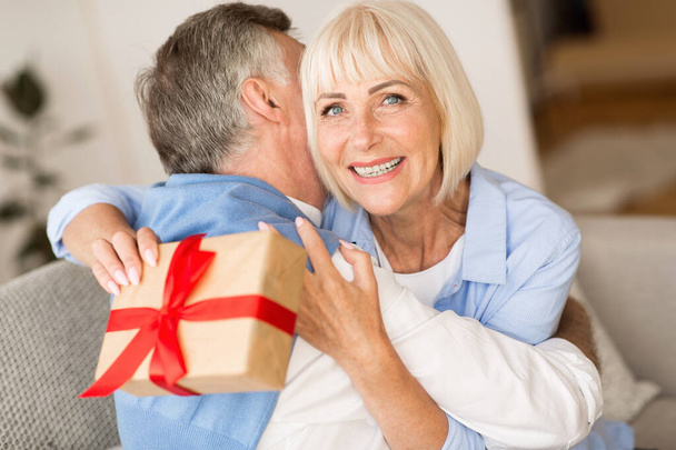 Present of love. Senior woman making surprise for husband - Fotó, kép