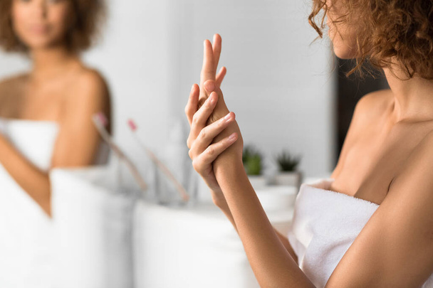 Μη αναγνωρίσιμη γυναίκα που εφαρμόζει κρέμα χεριών στο μπάνιο - Φωτογραφία, εικόνα