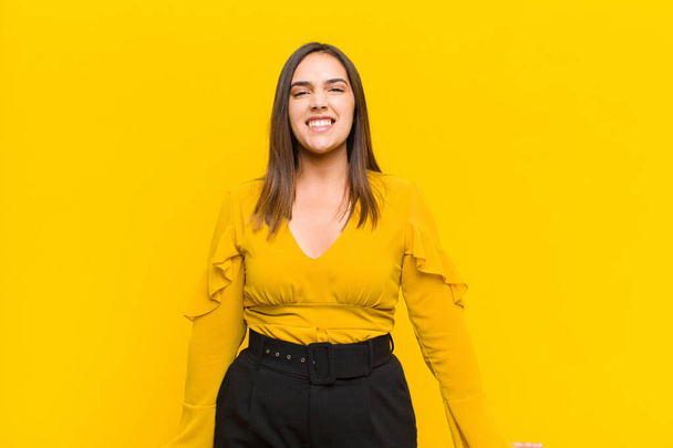 young pretty woman looking happy and pleasantly surprised, excited with a fascinated and shocked expression isolated against orange wall - Foto, imagen