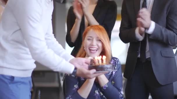 Syntymäpäiväjuhla nuorelle naispuoliselle kollegalle nykyaikaisessa toimistossa kakun kanssa
 - Materiaali, video