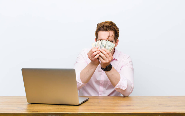 young red head businessman working in his desk, money concept - Photo, Image