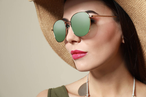 Beautiful woman in stylish sunglasses and hat on beige background - Fotoğraf, Görsel