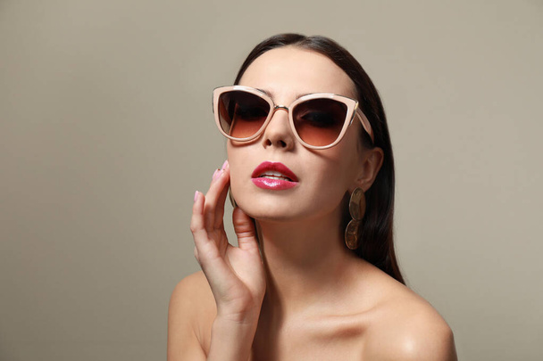 Beautiful woman in stylish sunglasses on beige background - Photo, Image