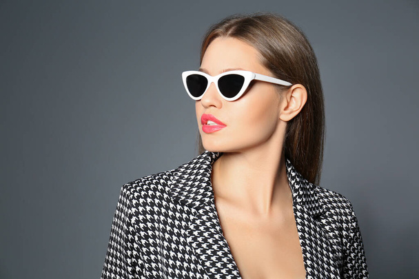 Young woman wearing stylish sunglasses on grey background - Foto, Bild