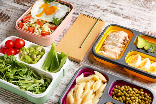 Carnet avec des aliments sains dans des boîtes à lunch sur fond blanc en bois. Concept de régime alimentaire
 - Photo, image
