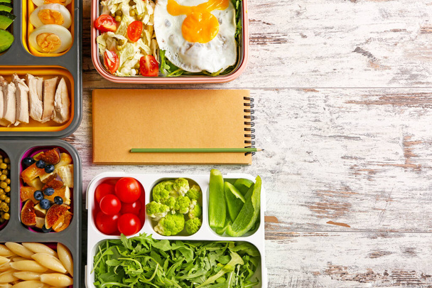 Quaderno con cibo sano in scatole da pranzo su sfondo di legno bianco. Concetto di dieta
 - Foto, immagini