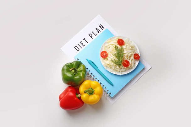 Σημειωματάριο με πρόγραμμα διατροφής και υγιεινά λαχανικά σε λευκό φόντο - Φωτογραφία, εικόνα