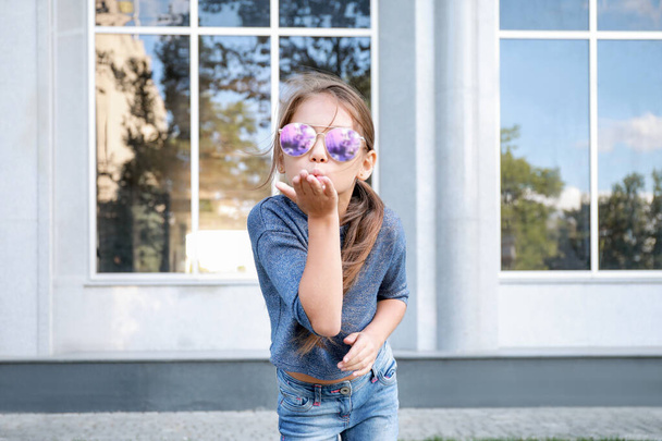 Portrait of cute fashionable girl blowing kiss outdoors - Фото, зображення