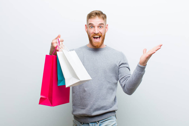 young red head man with shopping bags against white background - Foto, Bild