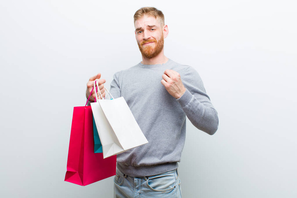 young red head man with shopping bags against white background - Фото, изображение