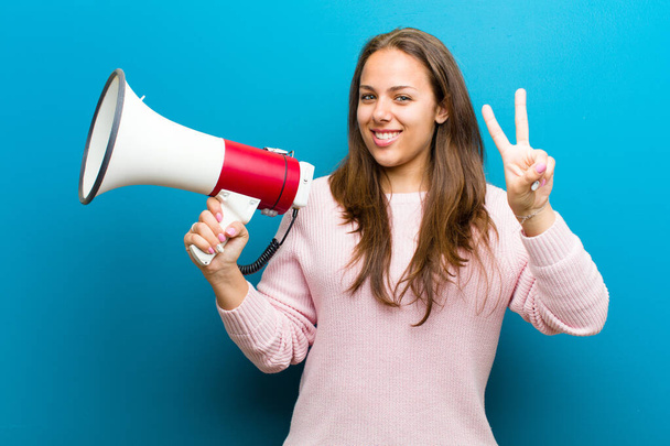 young woman with a megaphone against blue background - Foto, Imagem