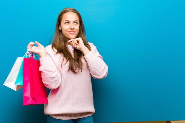 young woman with shopping bags against blue background - Foto, imagen