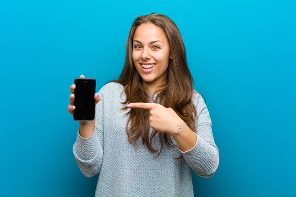 young woman with a mobile phone against blue background - Photo, Image