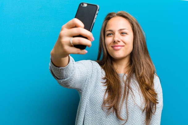 young woman with a mobile phone against blue background - Φωτογραφία, εικόνα