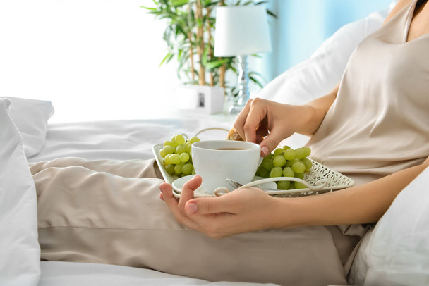Young woman having tasty breakfast in bed - 写真・画像