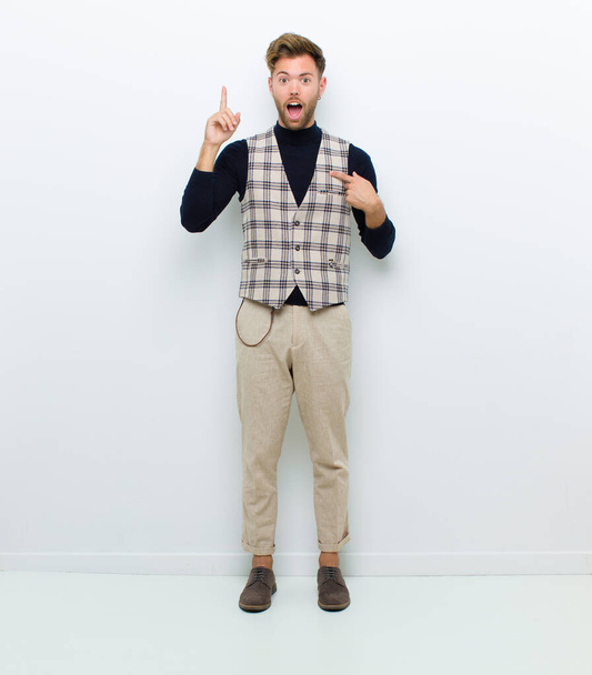young full body man feeling proud and surprised, pointing to self confidently, feeling like successful number one against white background - 写真・画像