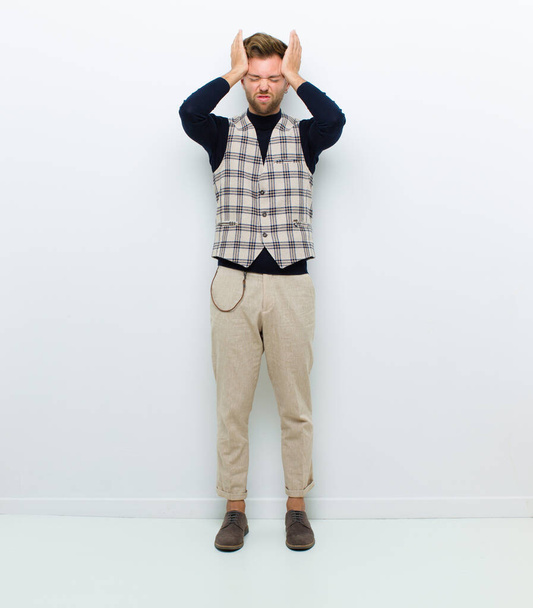 young full body man feeling stressed and anxious, depressed and frustrated with a headache, raising both hands to head against white background - Foto, Imagen