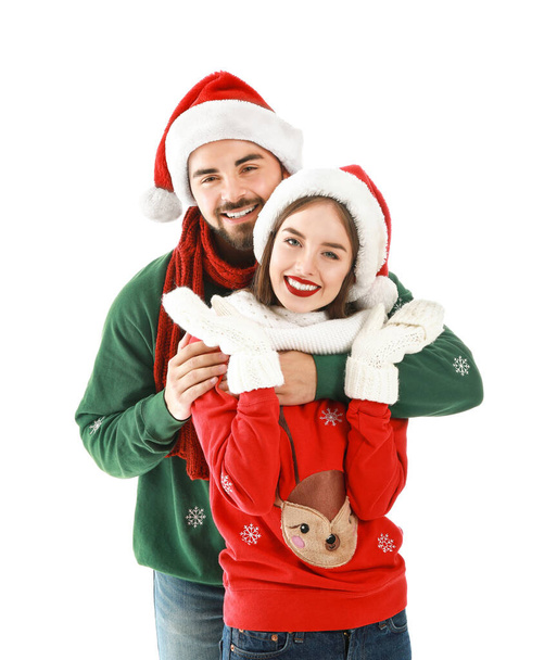 Ευτυχισμένο νεαρό ζευγάρι με Χριστουγεννιάτικα ρούχα σε λευκό φόντο - Φωτογραφία, εικόνα
