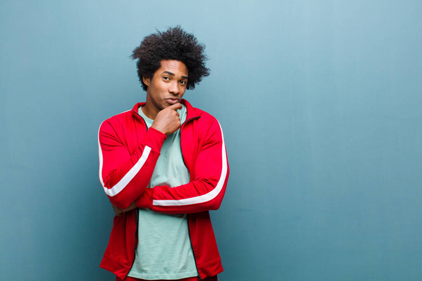young black sports man looking serious, confused, uncertain and thoughtful, doubting among options or choices against grunge wall - Fotoğraf, Görsel