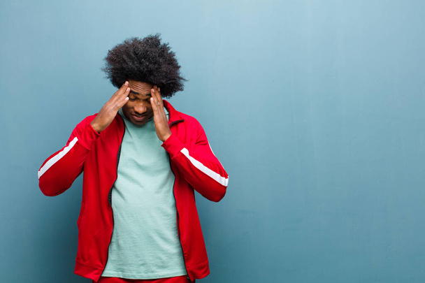 young black sports man looking stressed and frustrated, working under pressure with a headache and troubled with problems against grunge wall - Foto, imagen