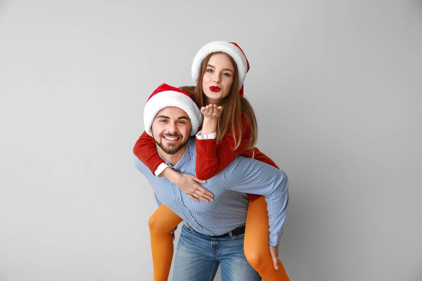 Feliz pareja joven en los sombreros de Santa sobre fondo claro
 - Foto, imagen