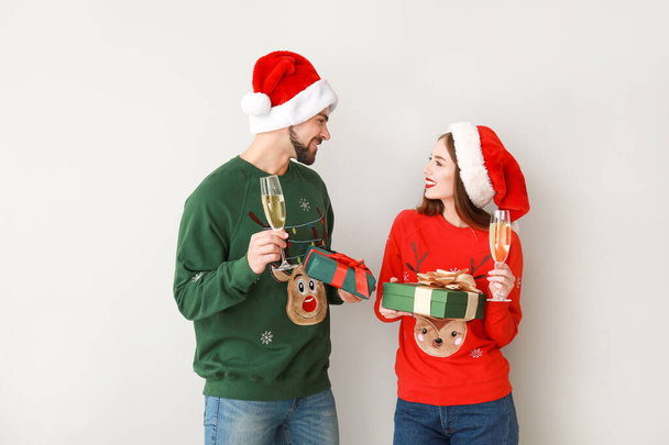 Onnellinen nuori pari joululahjoja ja samppanjaa kevyellä taustalla
 - Valokuva, kuva