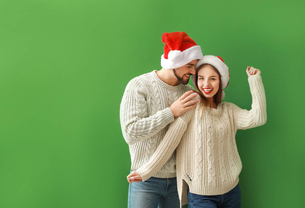 Happy young couple in Santa hats on color background - Φωτογραφία, εικόνα
