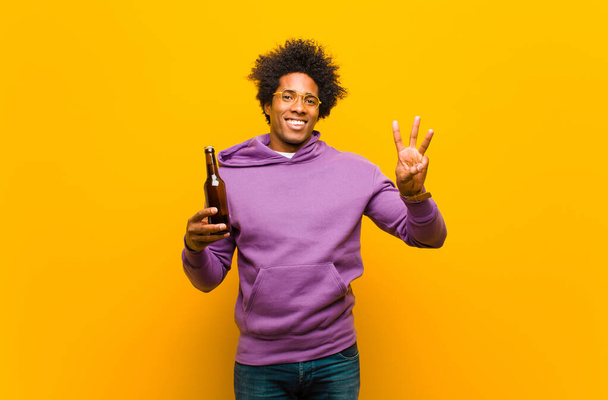young african american man with a beer against orange background - Фото, зображення