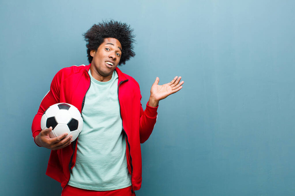 young black sports man with a soccer ball against blue grunge wa - Foto, Imagem