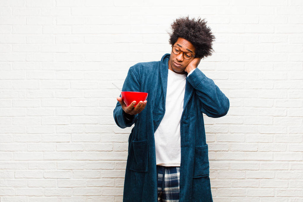 young black man wearing pajamas with a breakfast bowl against br - Фото, зображення