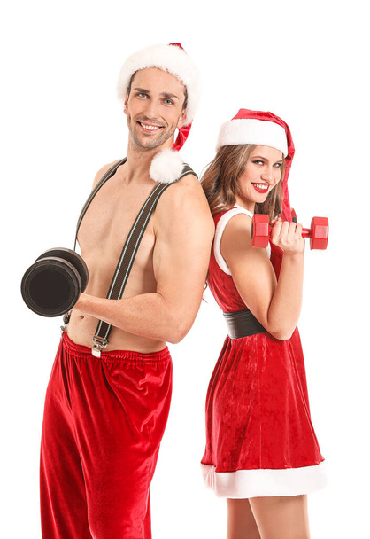 Jeune couple habillé en Père Noël avec haltères sur fond blanc
 - Photo, image