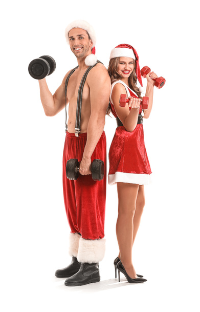 Young couple dressed as Santa Claus with dumbbells on white background - Foto, immagini