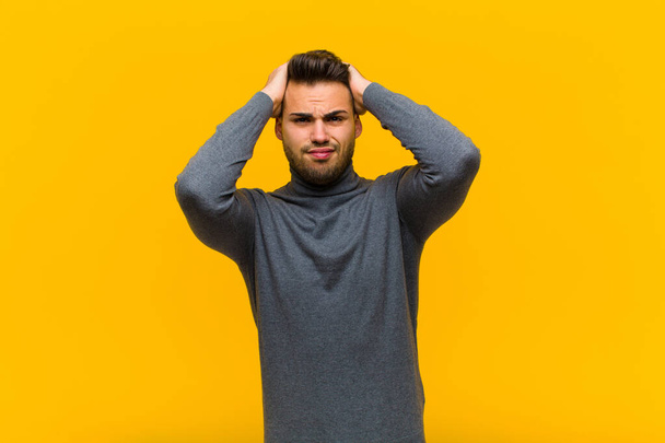 young hispanic man feeling frustrated and annoyed, sick and tired of failure, fed-up with dull, boring tasks against orange wall - Photo, image