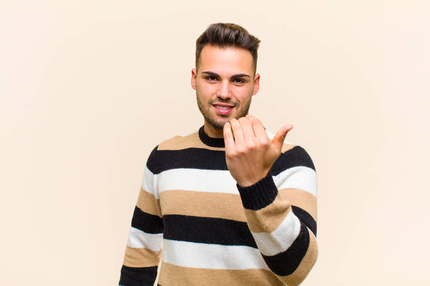 young hispanic man feeling happy, successful and confident, facing a challenge and saying bring it on! or welcoming you against isolated background - Фото, зображення