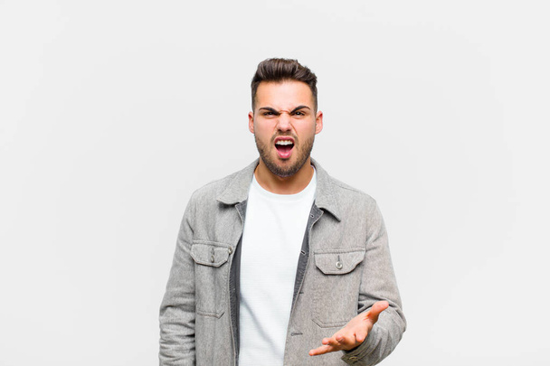 young hispanic man looking angry, annoyed and frustrated screaming wtf or whats wrong with you against gray background  - Fotografie, Obrázek