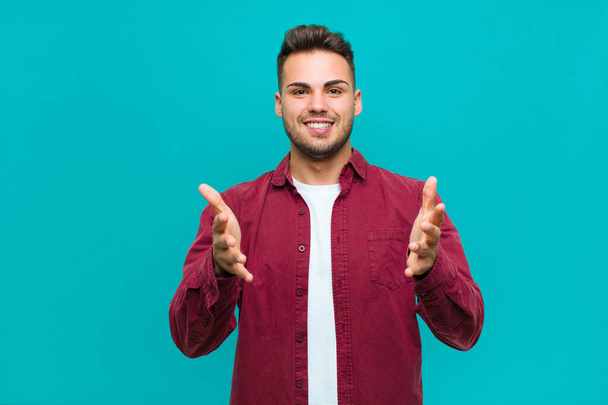 young hispanic man feeling happy, astonished, lucky and surprised, like saying omg seriously? Unbelievable against blue background - Foto, Bild