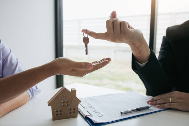 Hand des Immobilienmaklers übergibt den Schlüssel an neue Hauseigentümer in - Foto, Bild