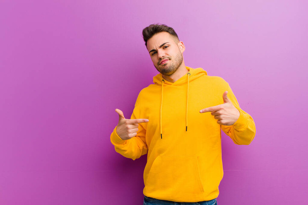 joven hombre hispano con mirada casual contra fondo púrpura
 - Foto, Imagen