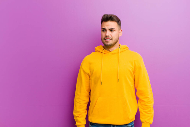 young hispanic man with casual look against purple background - Fotoğraf, Görsel