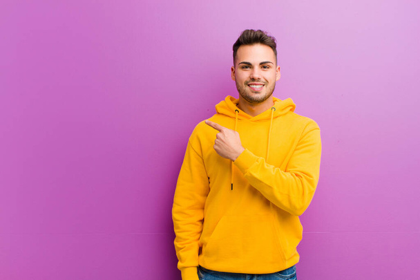 young hispanic man with casual look against purple background - Zdjęcie, obraz