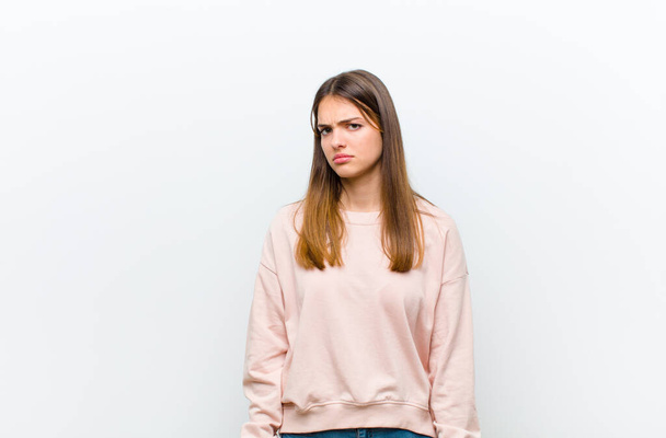 young pretty woman feeling sad, upset or angry and looking to the side with a negative attitude, frowning in disagreement against white background - Fotografie, Obrázek
